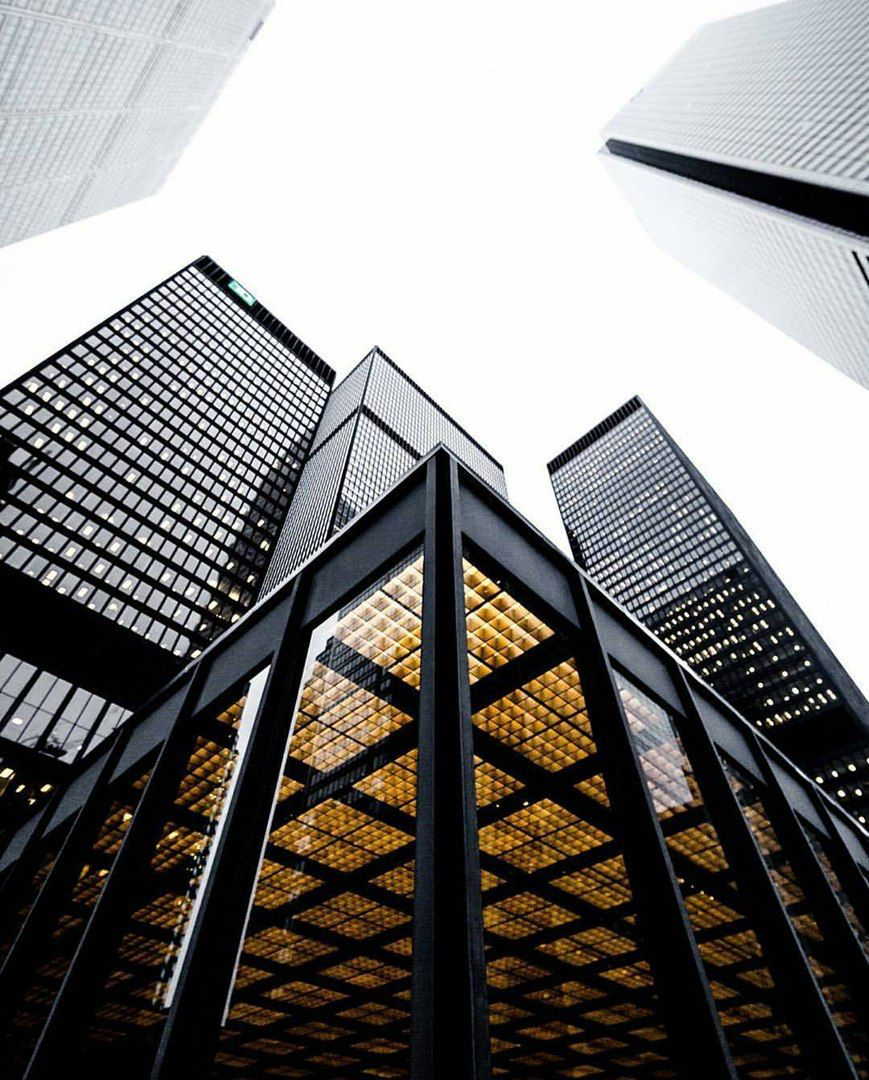 Upward view of golden-lit skyscrapers against a bright sky