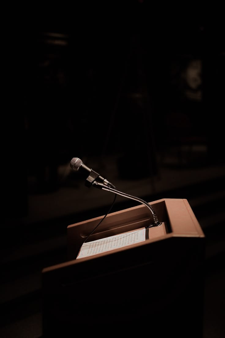 A spotlit podium and microphone on a stage